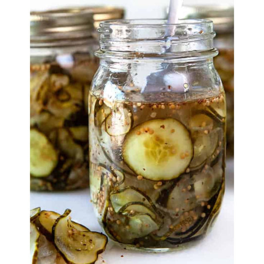 Sliced cucumbers, onions, and spices in a jar, ready to be refrigerated for homemade pickles.