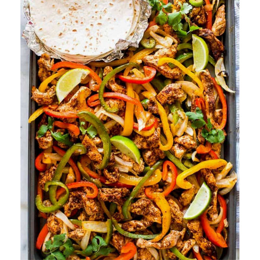 A pan filled with chicken fajita sheet pan seasoning, peppers, and onions.