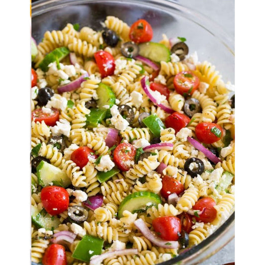 Pasta salad with tomatoes, cucumbers, olives, and feta cheese on a white plate.