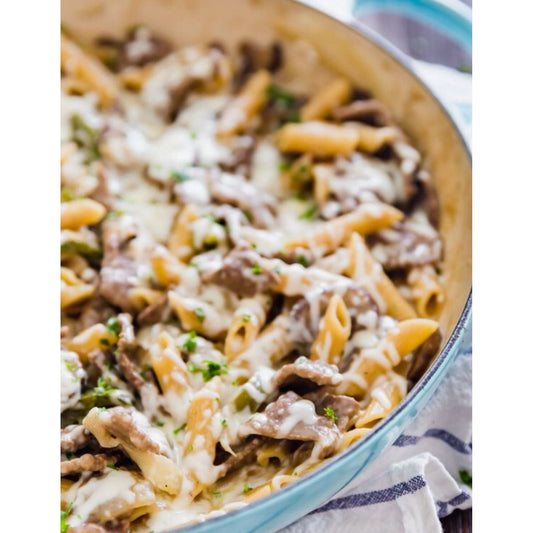 Philly Cheesesteak Pasta in a blue skillet - a delicious and savory pasta dish topped with melted cheese.