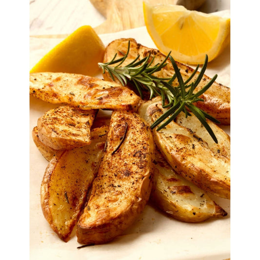 Oven roasted potato wedges with lemon slices on a plate. Perfect side dish.