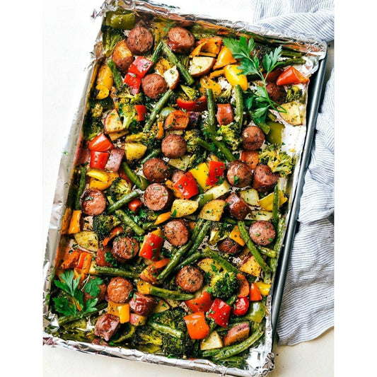 A sheet pan filled with a colorful medley of vegetables and savory sausage.