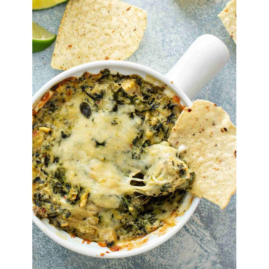 Spinach and cheese dip in a white bowl with tortilla chips - a creamy, savory dip perfect for snacking.