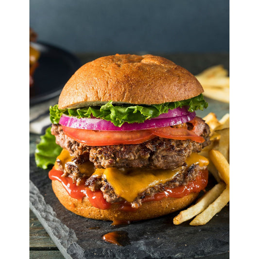 An appetizing hamburger featuring cheese, onions, and tomatoes, a classic steakhouse favorite.