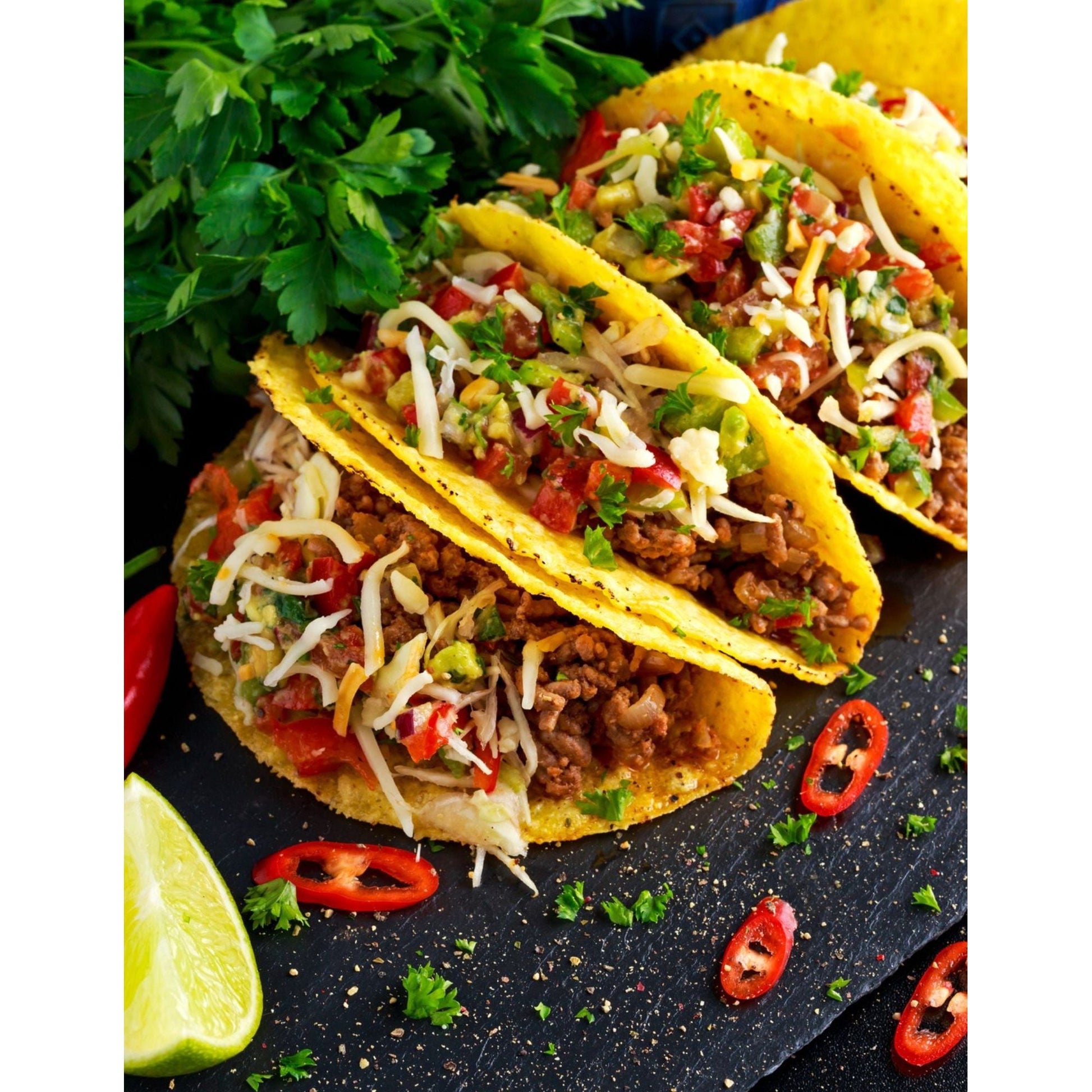 Three delicious tacos filled with meat and vegetables, beautifully presented on a black slate.