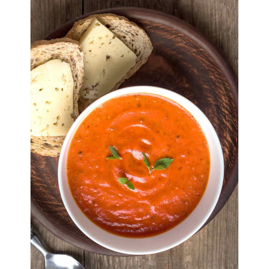 Tomato Basil soup with bread and cheese on a wooden table.