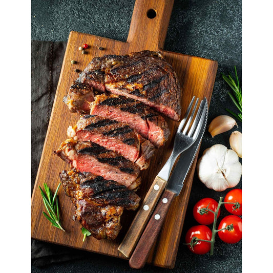 Grilled steak with colorful vegetables and aromatic herbs beautifully arranged on a wooden cutting board.
